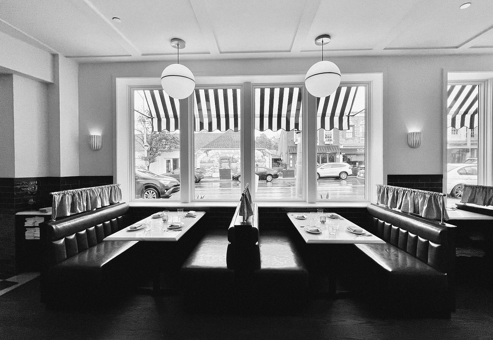 A dining room of banquettes and tables set for service